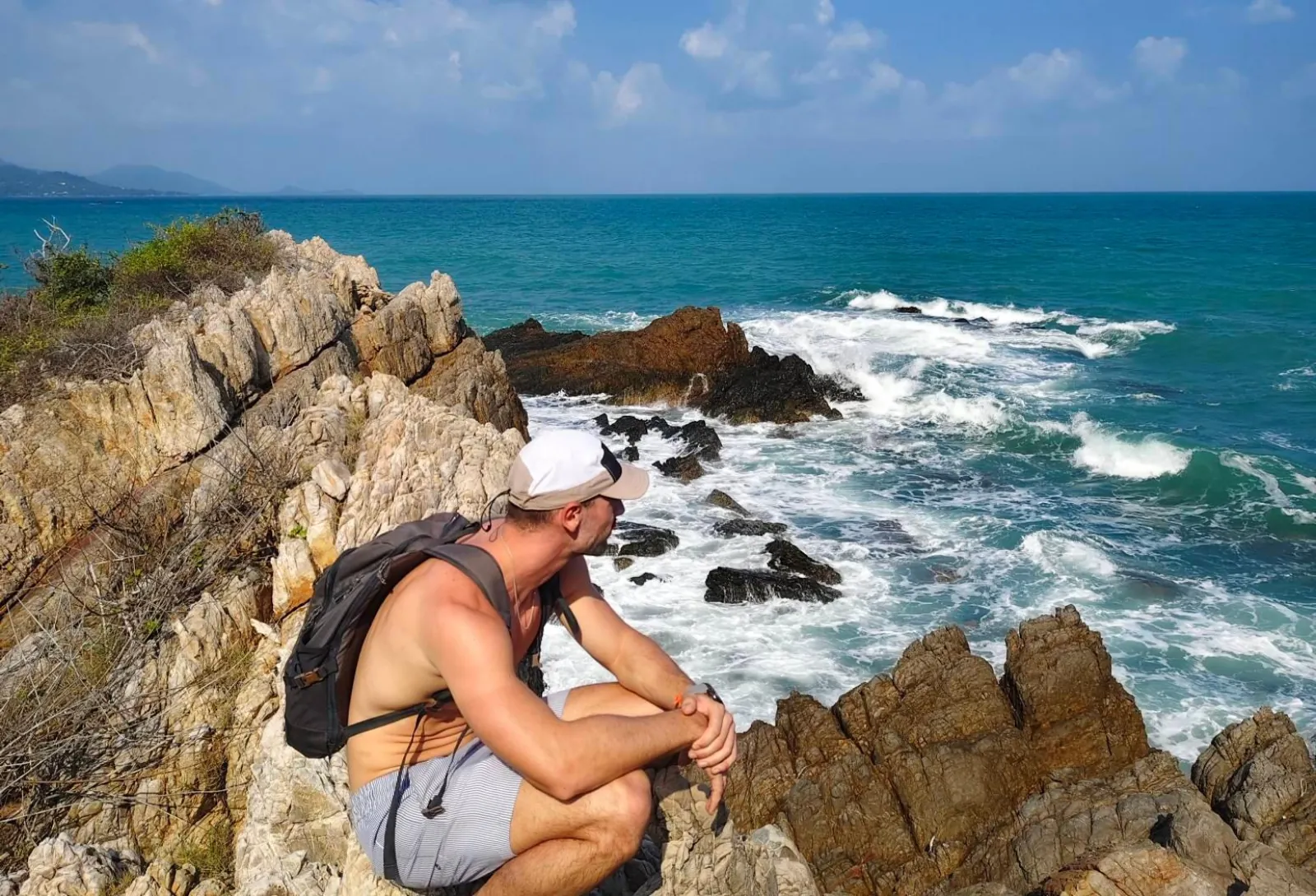 A hiker resting on the rocks above the surf on the viewpoint walk