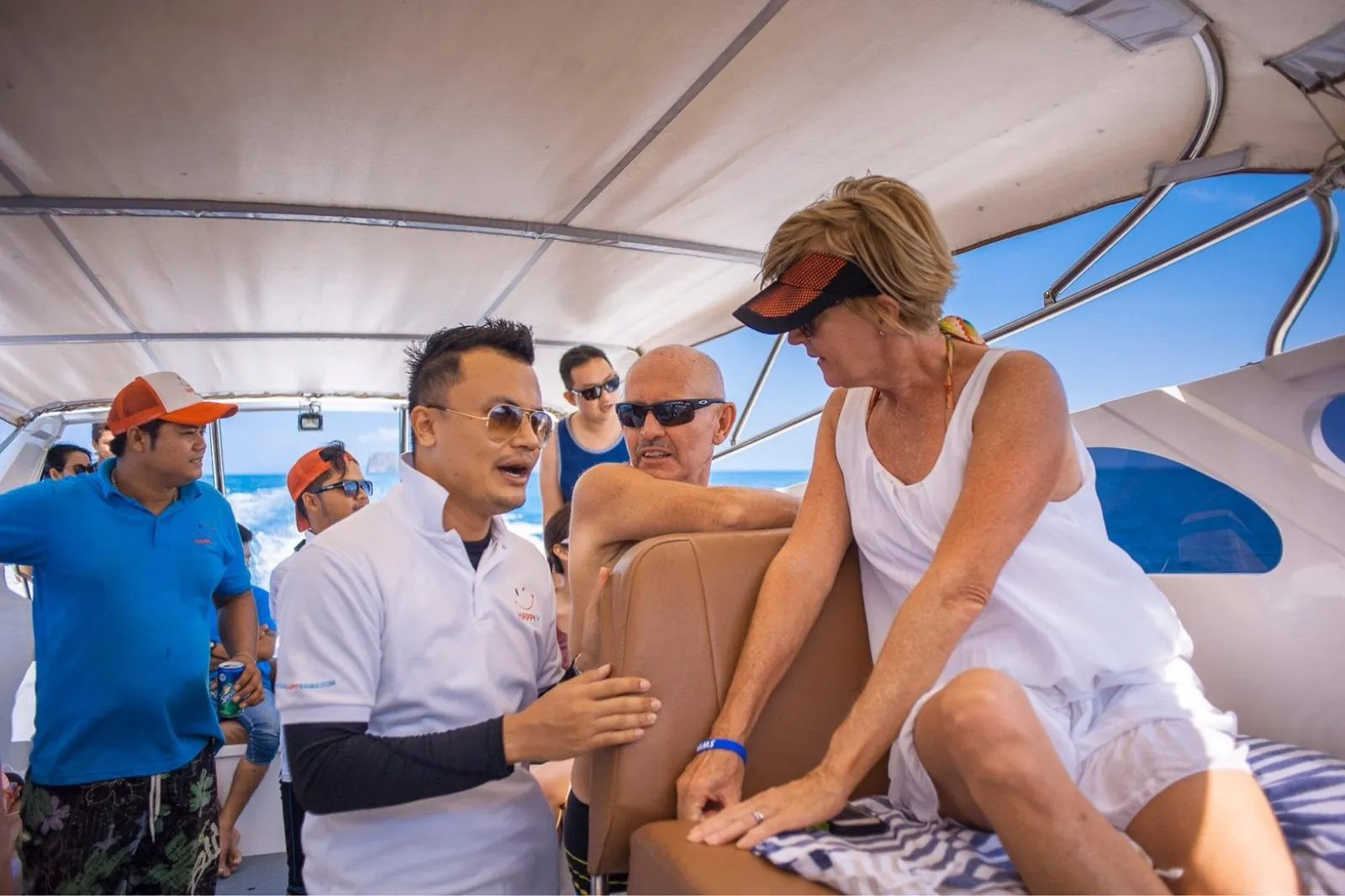 A guide briefing seated passengers under the speedboat canopy before departure