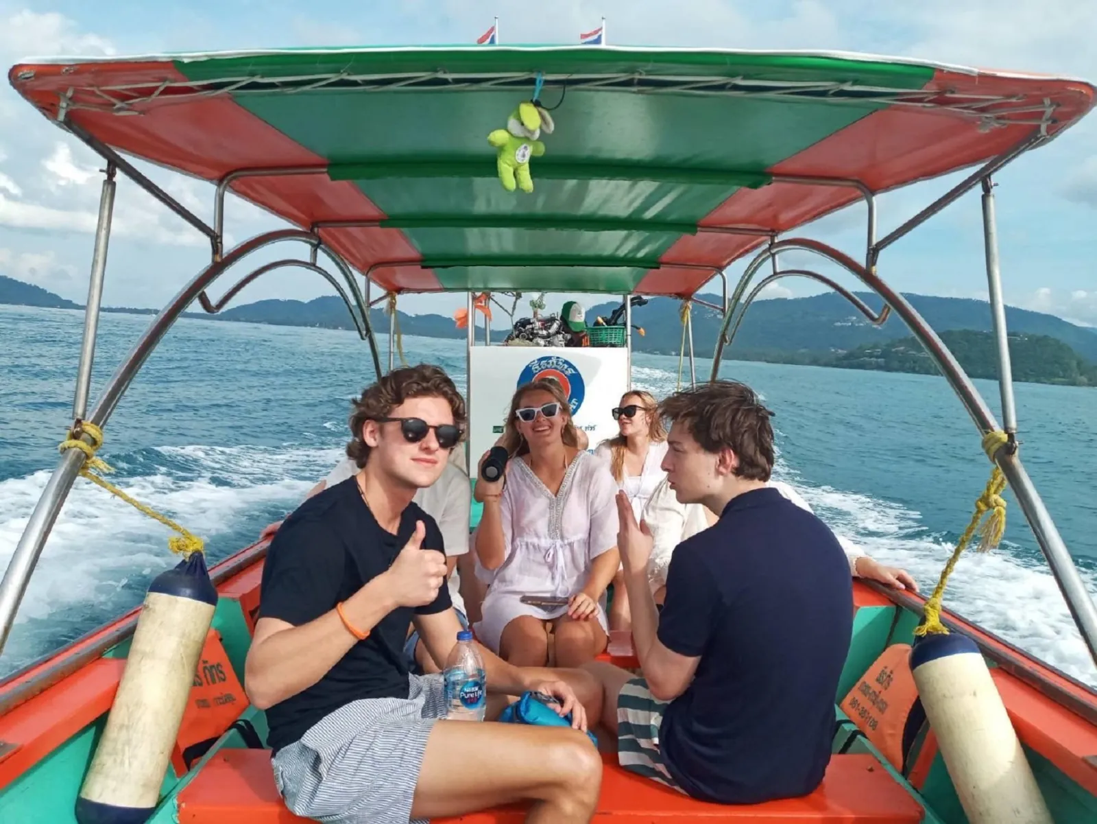 Guests seated under the red canopy of a longtail boat during the crossing