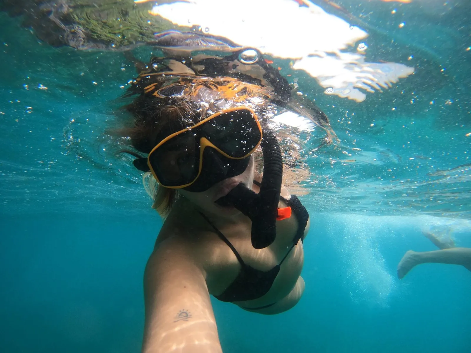 A snorkeller underwater in a mask with fish in the background